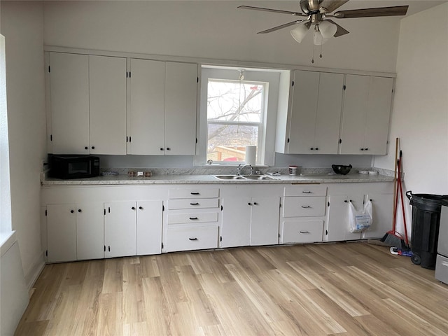 kitchen featuring light wood-type flooring, sink, and white cabinets