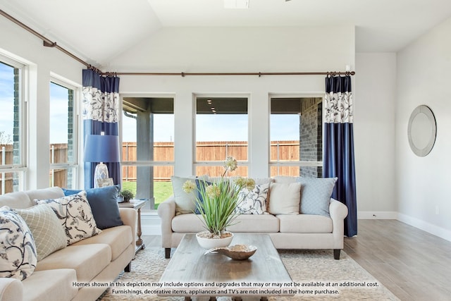 living room featuring vaulted ceiling, a wealth of natural light, and light hardwood / wood-style flooring