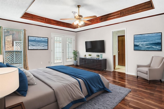 bedroom with ceiling fan, a tray ceiling, ornamental molding, dark hardwood / wood-style flooring, and french doors