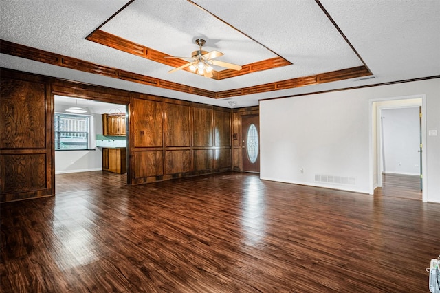 unfurnished living room with a healthy amount of sunlight, dark wood-type flooring, and a tray ceiling