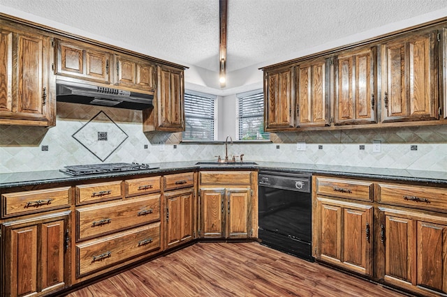 kitchen featuring tasteful backsplash, dishwasher, sink, stainless steel gas cooktop, and light hardwood / wood-style flooring