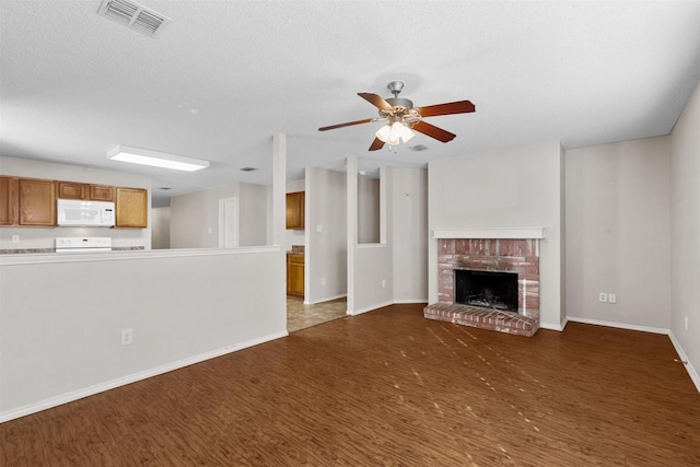 unfurnished living room featuring ceiling fan, a fireplace, dark hardwood / wood-style floors, and a textured ceiling