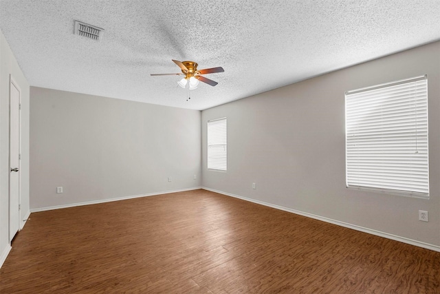 unfurnished room with a textured ceiling, dark wood-type flooring, and ceiling fan