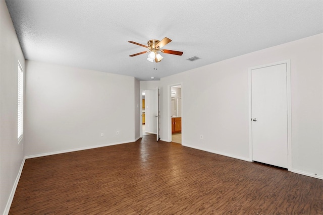 spare room featuring dark wood-type flooring, a textured ceiling, and ceiling fan