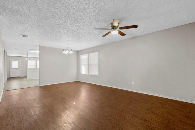 unfurnished room featuring ceiling fan with notable chandelier, light hardwood / wood-style floors, and a textured ceiling