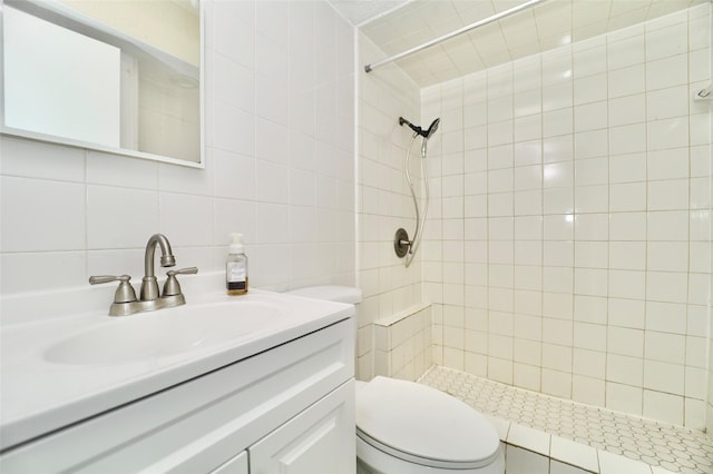 bathroom with tiled shower, toilet, tasteful backsplash, tile walls, and vanity