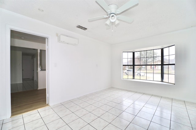 spare room featuring ceiling fan, an AC wall unit, a textured ceiling, and light tile patterned floors