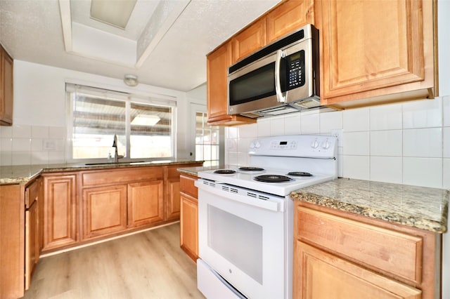 kitchen with sink, light hardwood / wood-style flooring, white range with electric stovetop, tasteful backsplash, and light stone counters