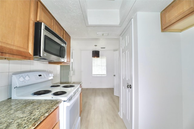 kitchen featuring white range with electric cooktop, hanging light fixtures, light stone counters, tasteful backsplash, and light wood-type flooring