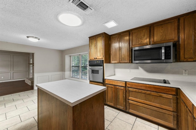 kitchen featuring wall oven, light tile patterned floors, black electric cooktop, and a center island