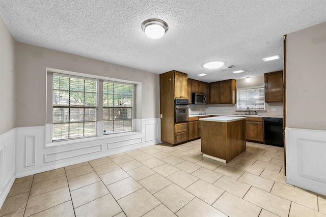 kitchen featuring light tile patterned floors, sink, stainless steel appliances, a center island, and a textured ceiling