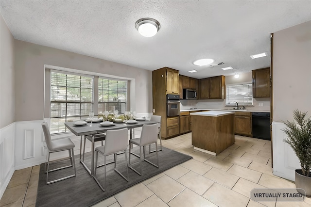 kitchen featuring stainless steel appliances, sink, a center island, and light tile patterned floors