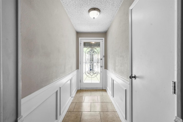 entryway with light tile patterned flooring and a textured ceiling