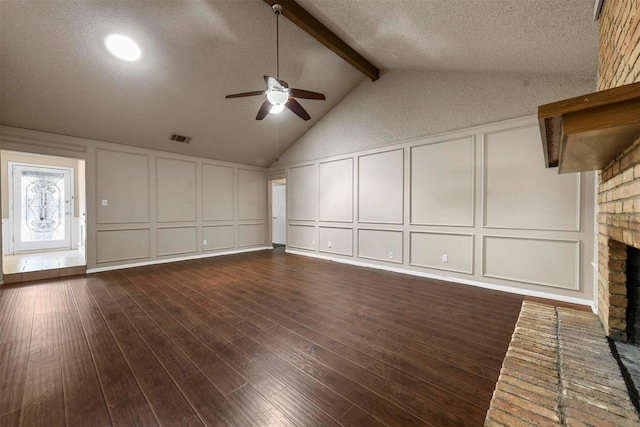 unfurnished living room with vaulted ceiling with beams, dark wood-type flooring, a fireplace, and a textured ceiling