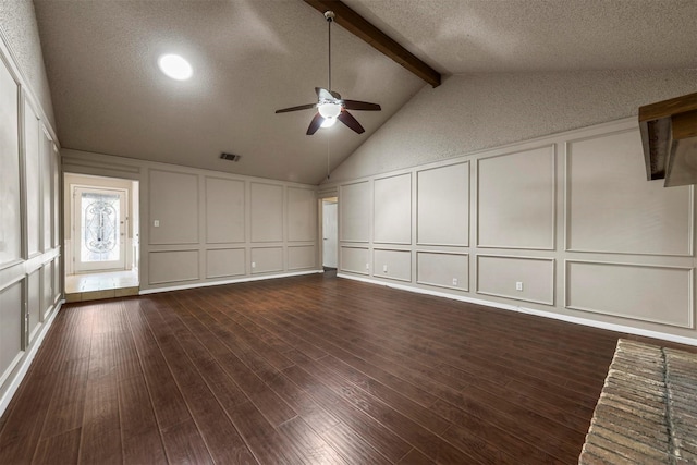 unfurnished living room featuring lofted ceiling with beams, ceiling fan, dark wood-type flooring, and a textured ceiling