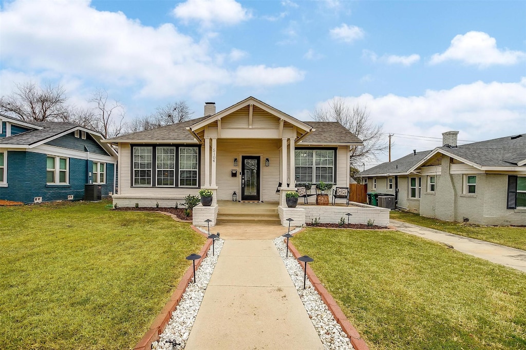 bungalow with a front yard and central air condition unit