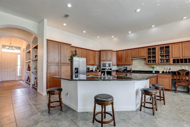 9801 Georgia Ave, Denton, TX 76207 - kitchen with appliances with stainless steel finishes, brown cabinets, a kitchen bar, a large island, and vaulted ceiling