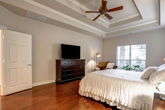 bedroom with crown molding, a tray ceiling, dark hardwood / wood-style floors, and ceiling fan