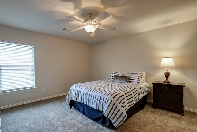 bedroom with ceiling fan, light colored carpet, and multiple windows