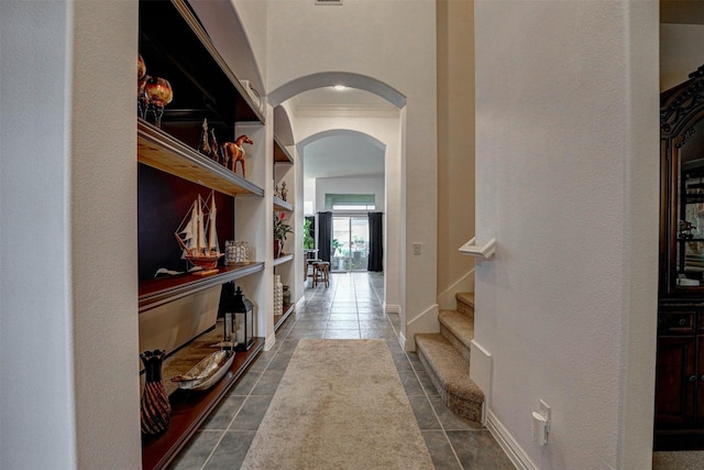 hallway featuring crown molding, dark tile patterned flooring, and built in features