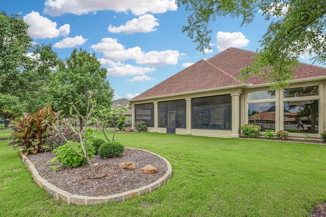 rear view of house with a yard and a sunroom