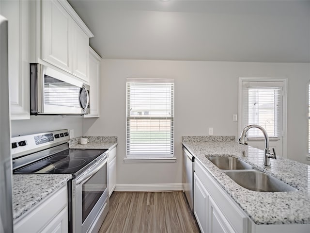 kitchen with sink, light hardwood / wood-style flooring, white cabinetry, stainless steel appliances, and light stone countertops