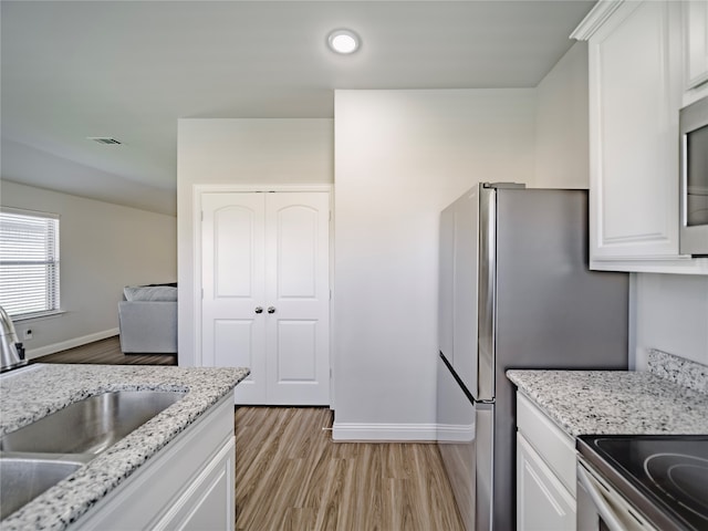 kitchen with white cabinetry, light stone countertops, sink, and light hardwood / wood-style floors