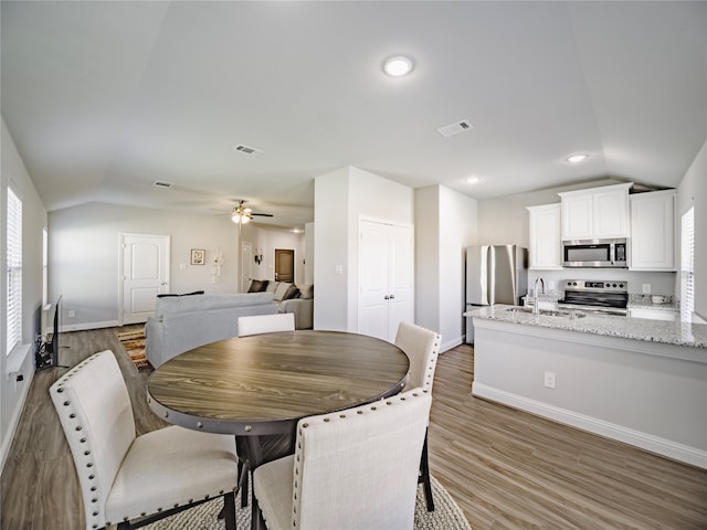 dining area featuring sink, vaulted ceiling, wood-type flooring, and ceiling fan