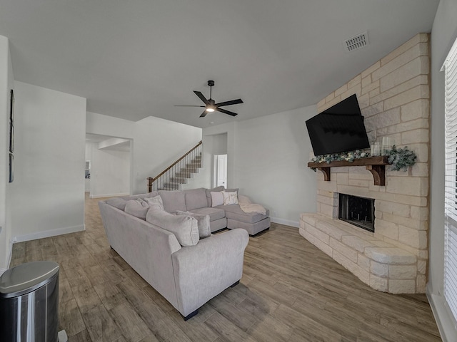 living room featuring light hardwood / wood-style flooring, a fireplace, and ceiling fan