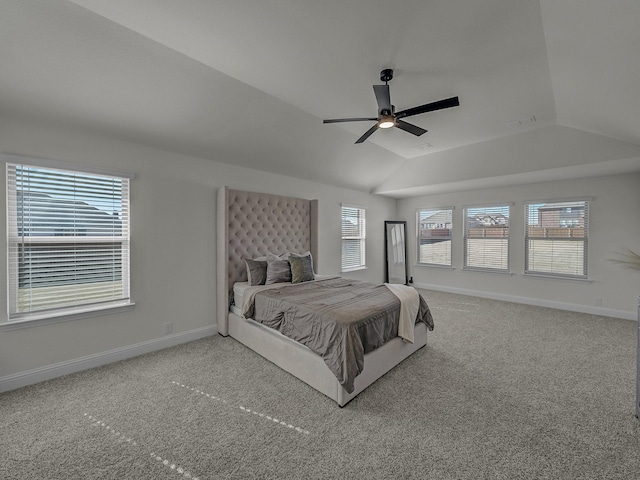 carpeted bedroom featuring ceiling fan, a tray ceiling, vaulted ceiling, and multiple windows