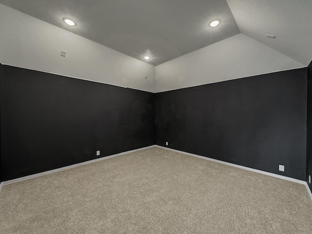 carpeted spare room featuring vaulted ceiling and a textured ceiling