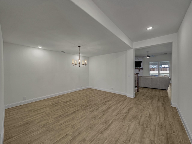 interior space with ceiling fan with notable chandelier and light hardwood / wood-style flooring