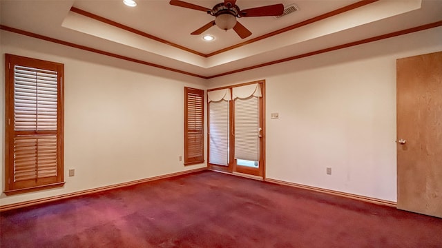 carpeted empty room with ceiling fan, ornamental molding, and a raised ceiling