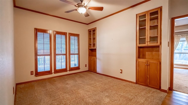 carpeted empty room with ceiling fan and ornamental molding