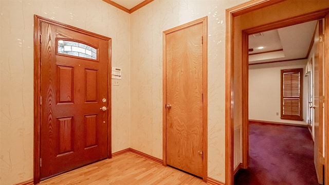 entrance foyer featuring crown molding, a raised ceiling, and light wood-type flooring