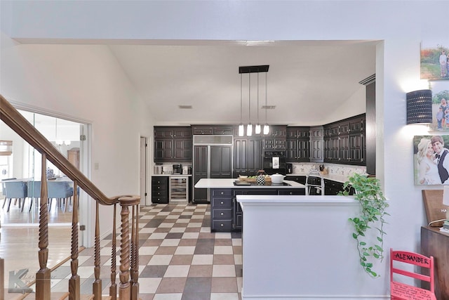 kitchen with wine cooler, hanging light fixtures, dark brown cabinets, and vaulted ceiling