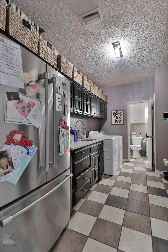 kitchen featuring separate washer and dryer, high quality fridge, sink, and a textured ceiling