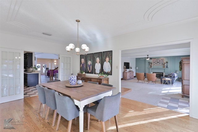 dining area with ceiling fan with notable chandelier, light hardwood / wood-style floors, and french doors