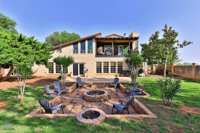 back of property featuring a patio, a balcony, a lawn, and a fire pit