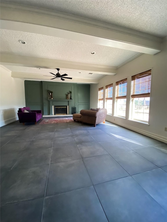 unfurnished living room with ceiling fan, a textured ceiling, and beam ceiling