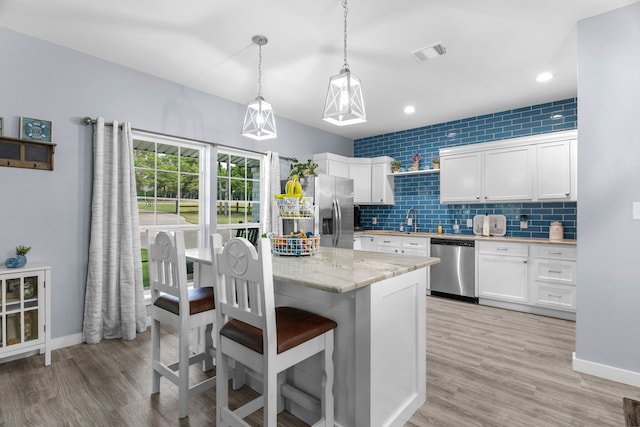 86593 N State Highway 289, Pottsboro, TX 75076 - kitchen featuring hanging light fixtures, stainless steel appliances, light hardwood / wood-style floors, white cabinets, and decorative backsplash