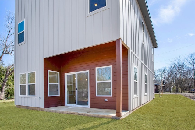 back of house with a patio, a lawn, and board and batten siding