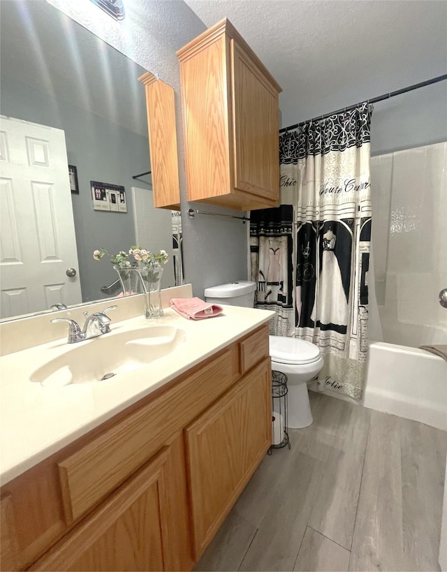 full bathroom featuring wood-type flooring, shower / bath combination with curtain, vanity, toilet, and a textured ceiling