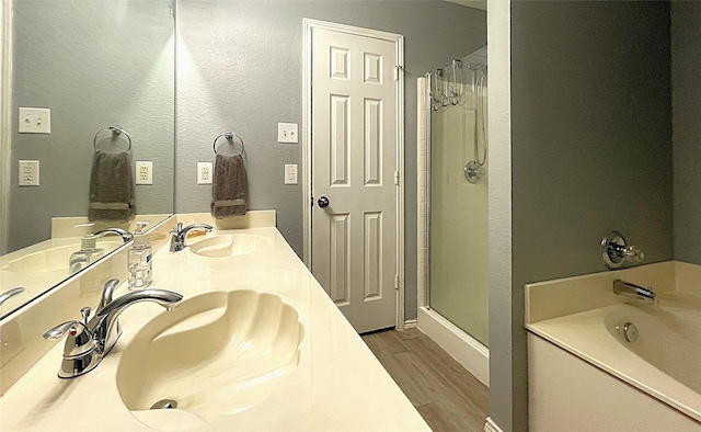 bathroom with wood-type flooring, shower with separate bathtub, and vanity