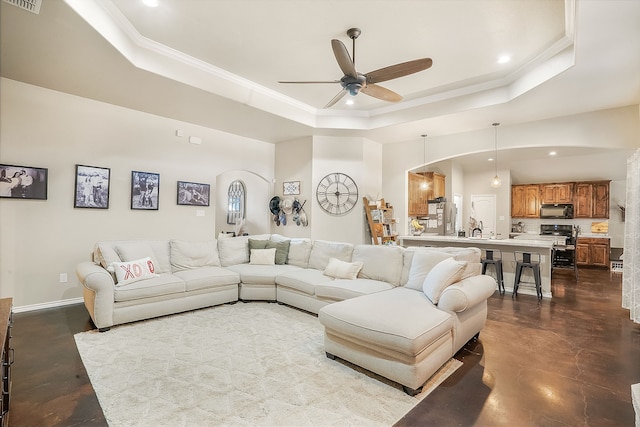 living room featuring ornamental molding, concrete floors, ceiling fan, and a tray ceiling