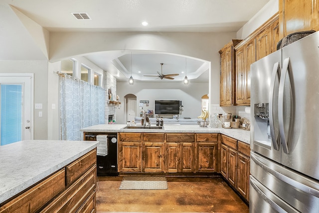 kitchen featuring stainless steel refrigerator with ice dispenser, black dishwasher, a raised ceiling, ceiling fan, and backsplash