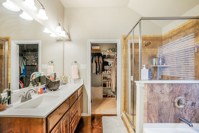 bathroom featuring vanity, a shower with shower door, and vaulted ceiling