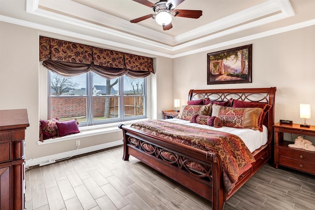 bedroom featuring a raised ceiling, ornamental molding, hardwood / wood-style flooring, and ceiling fan