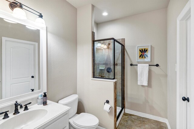 bathroom with vanity, toilet, and a shower with door