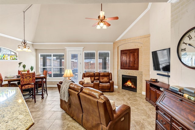 tiled living room with crown molding, a large fireplace, high vaulted ceiling, and ceiling fan with notable chandelier